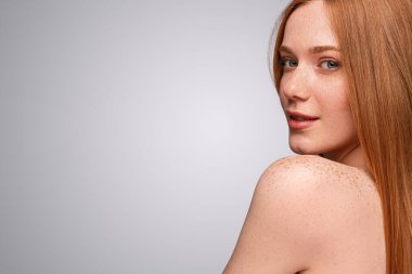 Çilli genç bayan kameraya bakıyor ve gülümsüyor.