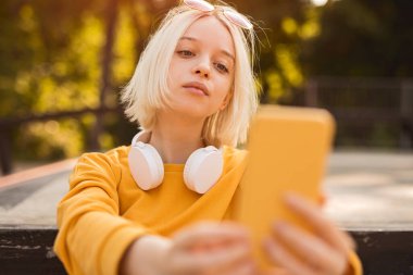 Şık bir genç parkta selfie çekiyor.