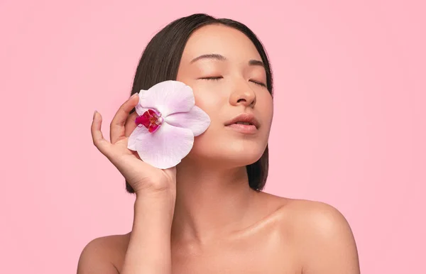 亚洲女人用鲜花触摸脸 — 图库照片