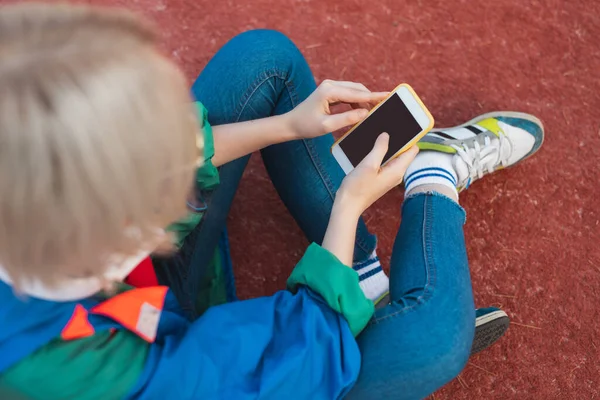 Неузнаваемый подросток, использующий смартфон на детской площадке — стоковое фото