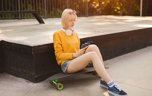 Pattinatore adolescente con smartphone nel parco — Foto Stock