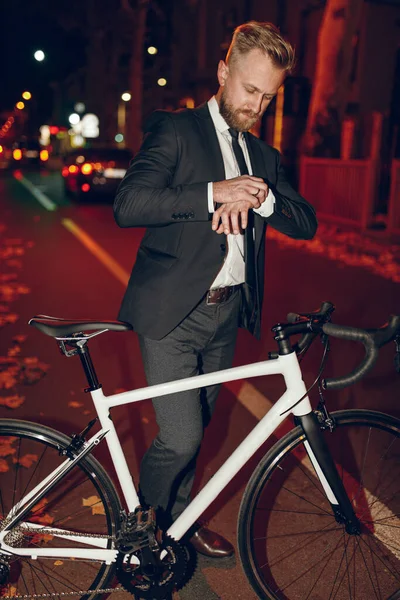 Empresario con reloj de control de bicicleta por la noche — Foto de Stock