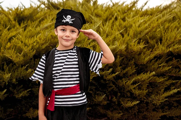 Милий хлопчик у піратському костюмі, що стоїть під кущами — стокове фото