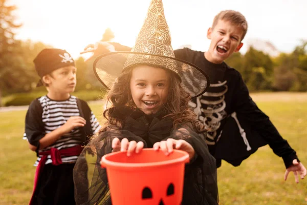 Glückliche Kinder in Halloween-Kostümen mit Süßigkeitensammler — Stockfoto