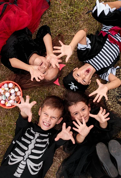 Щасливі діти в костюмах Хеллоуїна лежать на траві — стокове фото