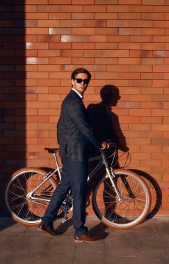 İş adamı bisikletini caddeye park ediyor.