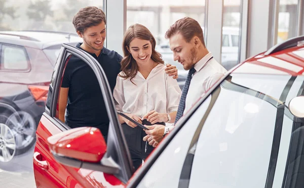 Dealer helping couple to choose car — Stock Photo, Image