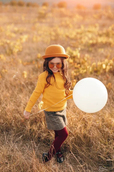 Stylowa dziewczynka z balonem na polu — Zdjęcie stockowe