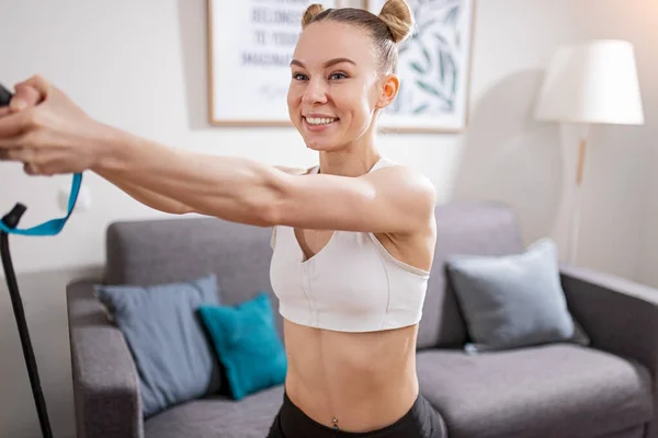 Cheerful sportswoman exercising at home — Stock Photo, Image