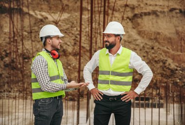 İnşaat alanında erkek müteahhitler konuşuyor.