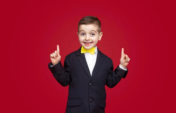 Grappige schooljongen glimlachend en omhoog wijzend — Stockfoto