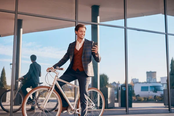 Empresario masculino usando smartphone en bicicleta —  Fotos de Stock