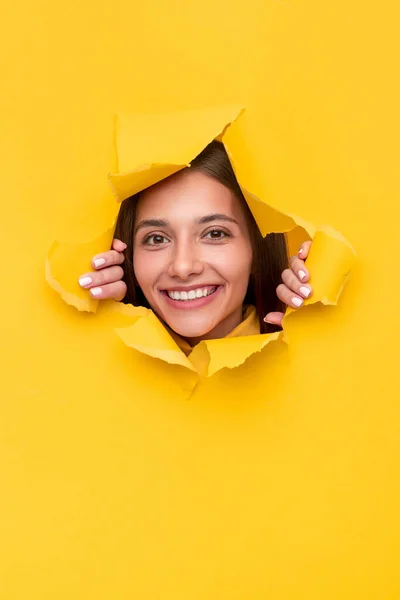 Jovem morena rasgando papel amarelo — Fotografia de Stock