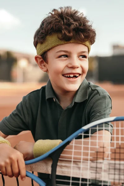 Šťastný malý tenista opírající se o síť — Stock fotografie
