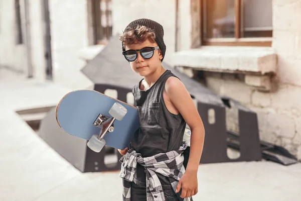Hipster niño con monopatín en la calle — Foto de Stock
