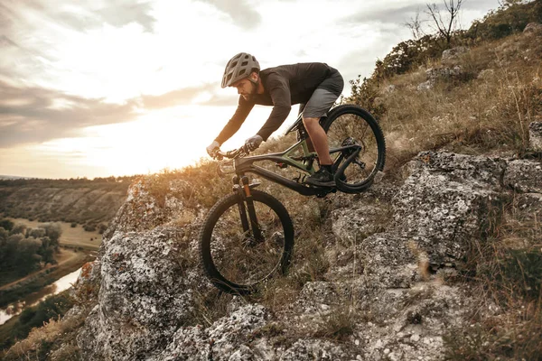 Homme à vélo sur la pente rocheuse au coucher du soleil — Photo