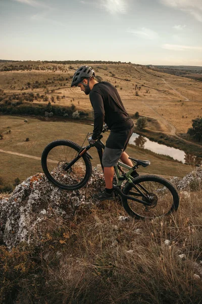 Ciclista masculino andar de bicicleta na rocha em colinas — Fotografia de Stock