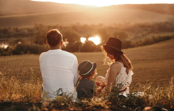 Família irreconhecível ao pôr do sol no campo — Fotografia de Stock