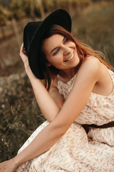 Счастливая женщина в шляпе отдыхает на летнем поле — стоковое фото