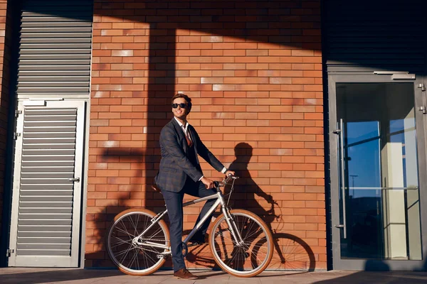 Веселый бизнесмен катается на велосипеде по улице — стоковое фото