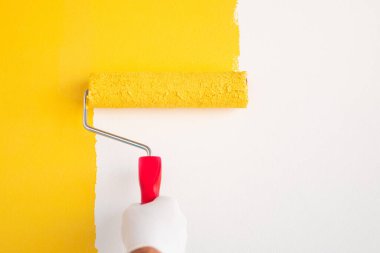 Tanımlanamayan işçi duvarları silindirle boyuyor.