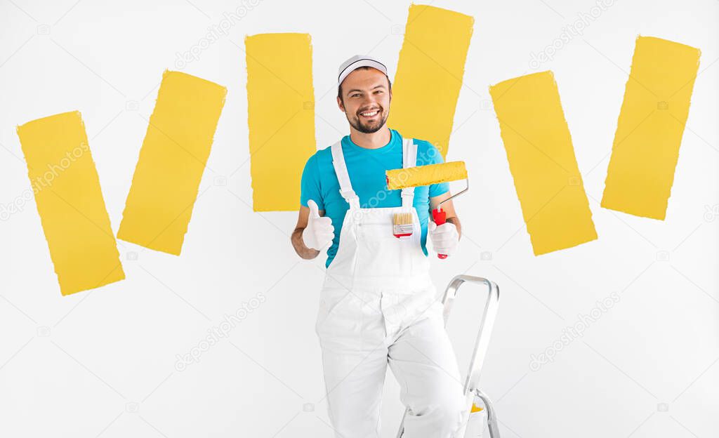 Cheerful decorator with paint roller showing thumb up