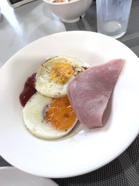 Sosis, sahanda yumurta ve jambonla servis edilen nefis kahvaltı seti. Mükemmel sabah yemeği konsepti, lezzetli yiyecekler, protein zengini diyet ve yaşam tarzı için klasik kahvaltı menüsü..