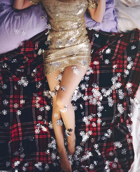 女孩在亮片礼服躺在床上与圣诞雪花 图库图片