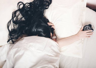 Bir çalar saat sabah holding beyaz yatakta el