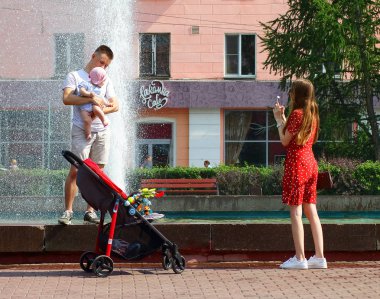 Genç bir anne bir çeşme arka planda bir çocuk ile genç bir baba fotoğraf çekmek