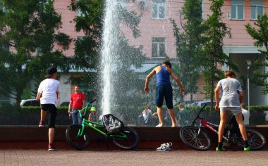 Yaz. ısı. Çeşme. bir çeşme arka planda Bisiklet ile çocuklar