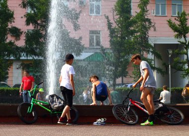 Yaz. ısı. Çeşme. bir çeşme arka planda Bisiklet ile çocuklar
