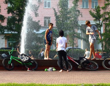Yaz. ısı. Çeşme. bir çeşme arka planda Bisiklet ile çocuklar