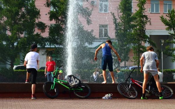 Yaz. ısı. Çeşme. bir çeşme arka planda Bisiklet ile çocuklar