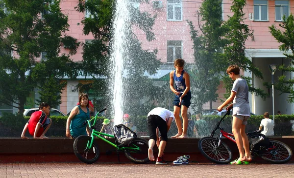 Yaz. ısı. Çeşme. bir çeşme arka planda Bisiklet ile çocuklar