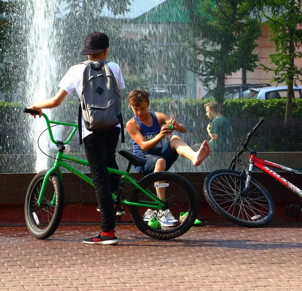 Yaz. ısı. Çeşme. bir çeşme arka planda Bisiklet ile çocuklar