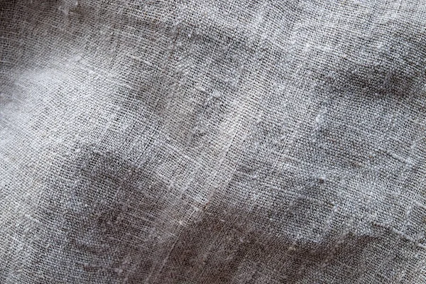 The texture of coarse linen gray fabric, close-up, weave of threads, natural material, eco-friendly fabric
