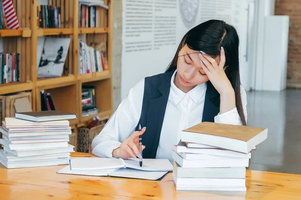 Cute Asian Girl Sitting In A Library Surrounded By Books Thinking About Studying Teen Student Prepares For Exams Takes Notes And Learns Stock Images Page Everypixel