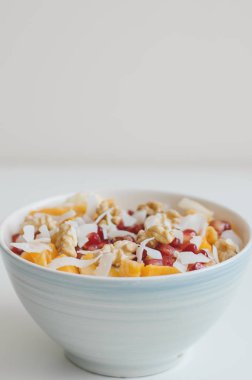 Meyve salatası nar taneleri, mango dilimleri, kızarmış kayısı, Hindistan cevizi pul, muz, mandalina ve ceviz ile dikey fotoğraf. Sağlıklı kahvaltı. Beslenme kavramı