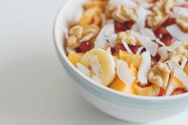 Muz, mango meyve, mandalina, Hindistan cevizi pul, nar taneleri ve cevizli salata kasesi. Vegan gıda. Vitaminler, karbonhidrat ve lif