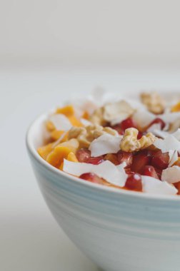 Sağlıklı meyve salatası. Nar taneleri, mango, Hindistan cevizi pul, mandalina, Kuru kayısı ve ceviz ile kase