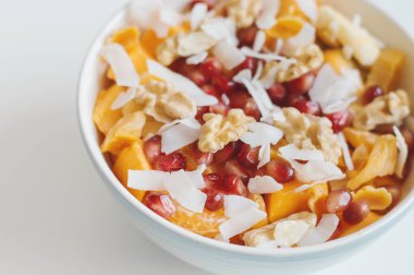 Sağlıklı vegan salata. Mango, mandalina, muz, Kuru Kayısı, ceviz, Hindistan cevizi pul, nar bir kase. Sağlıklı meyve tatlı