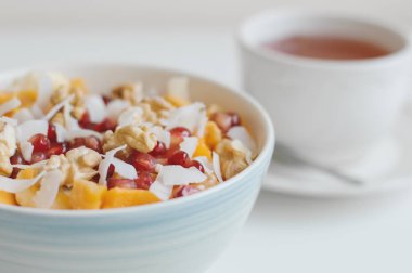 Kase taze meyve ve fındık bitkisel sıcak içecek bir fincan hizmet ile. Mango, muz, nar taneleri, Hindistan cevizi pul, mandalina ve ceviz. Sağlıklı tatlı