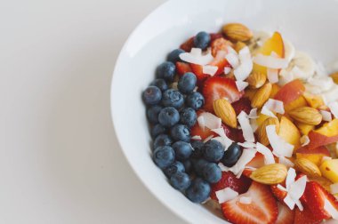 Taze meyve karışımı ile yulaf: yaban mersini, çilek, şeftali dilimleri, muz, badem ve Hindistan cevizi gevreği. Sağlıklı kahvaltı