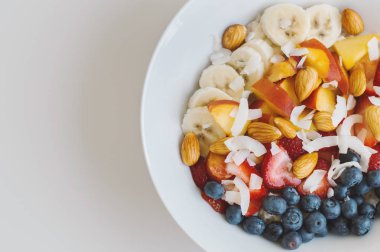 Sağlıklı kahvaltı: muz, şeftali, yaban mersini, çilek, Hindistan cevizi pul ve badem ile yulaf. Vegan gıda