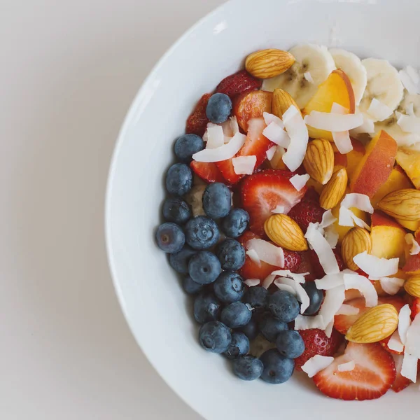 Sağlıklı kahvaltı yemek kare fotoğraf: yulaf, yaban mersini, çilek, şeftali, muz, badem ve Hindistan cevizi gevreği. Üstten görünüm