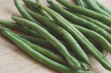 Bir avuç taze çiğ yeşil fasulye ahşap kesme tahtası üzerinde. Sağlıklı salata madde