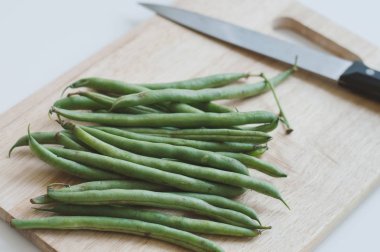 Taze çiğ yeşil fasulye ve ahşap kesme tahtası üzerinde büyük bir bıçak. Gıda içerikler