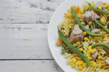 Ton balığı, Mısır ve fasulye gri ahşap arka plan ile makarna. Dengeli yemek