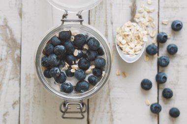 Hindistan cevizi sütü ile ahşap masa, üstten görünüm üzerinde taze bluberry gece yulaf ile batırılmış. Sağlıklı kahvaltı